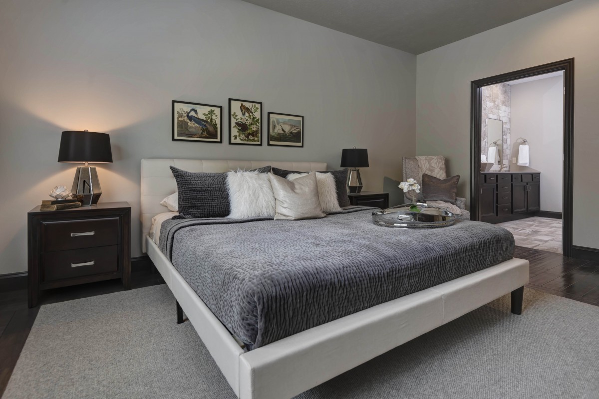 A modern and elegant bedroom with neutral tones, featuring a comfortable double bed, stylish lamps on bedside tables, and framed artwork above the headboard.