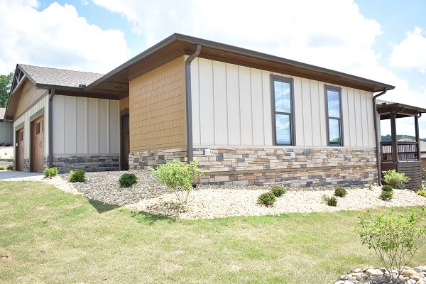 A modern house exterior with stone siding and landscaped yard.