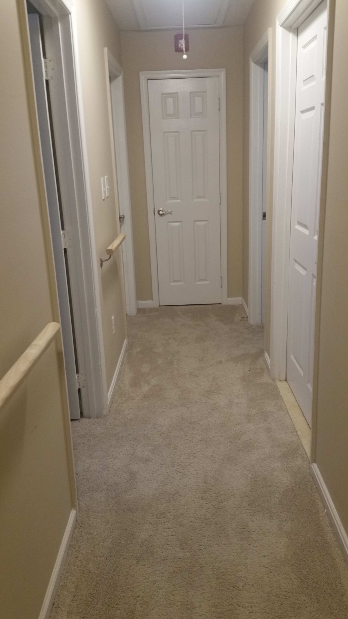 A carpeted hallway with multiple doors leading to different rooms.