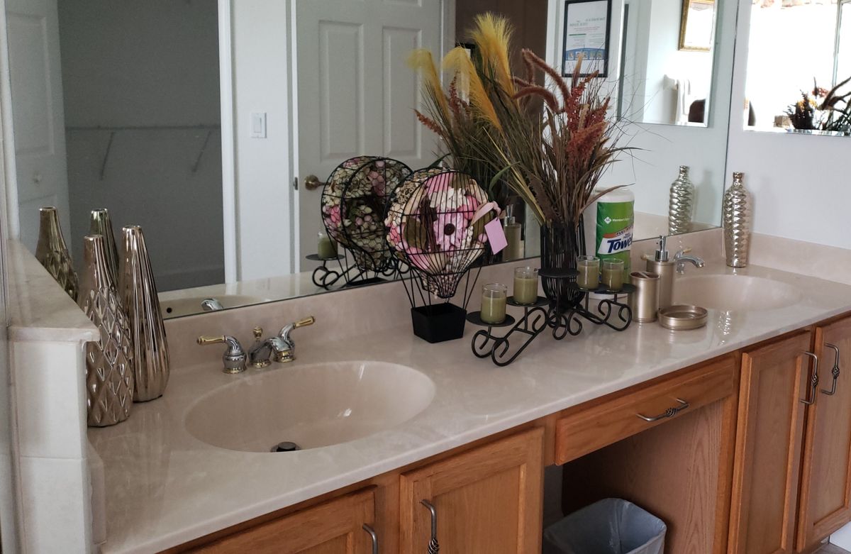 A bathroom countertop with a sink, mirror, and decorative flower arrangements.