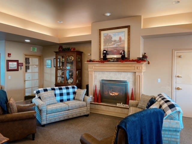 A cozy living room featuring a fireplace with surrounding decor, comfortable sofas, and armchairs.