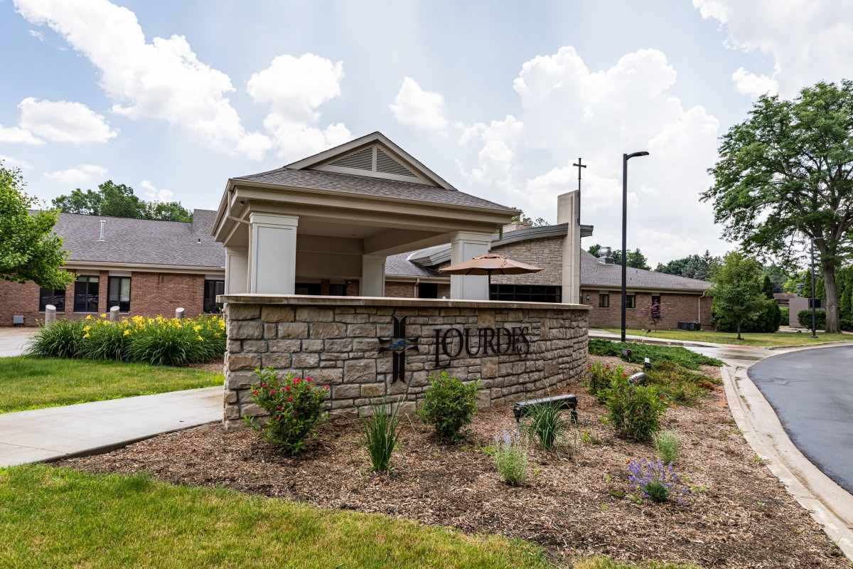 The entrance to a building complex featuring a landscaped area and signage.