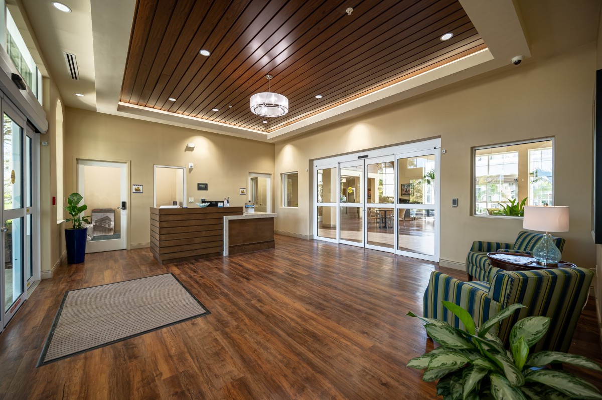A modern lobby with wood flooring and a welcoming reception desk.