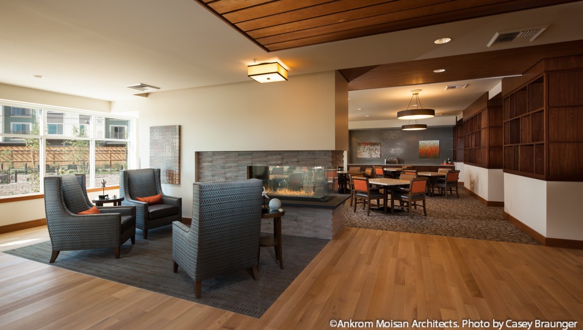 A modern interior with a cozy sitting area featuring a fireplace, complemented by a dining space in the background.