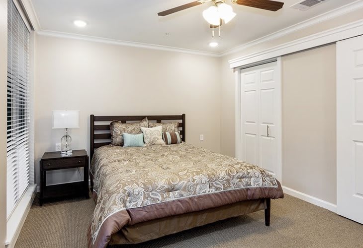 A cozy bedroom with a comfortable bed, nightstand, and ceiling fan.