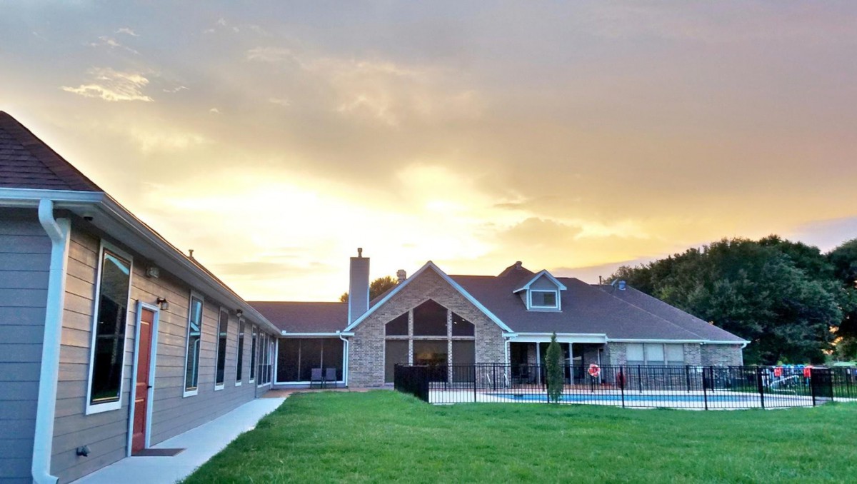 A beautiful house with a large lawn at sunset.