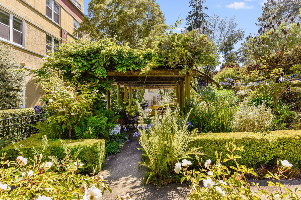 A lush garden featuring a gazebo surrounded by vibrant greenery and flowers.