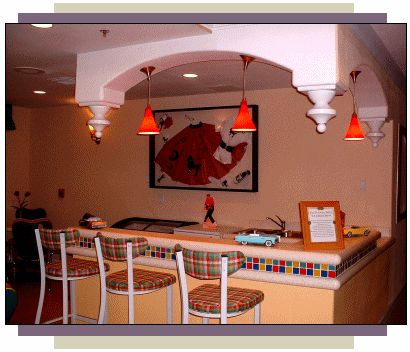 A cozy bar with high stools, warm lighting, and colorful decor.