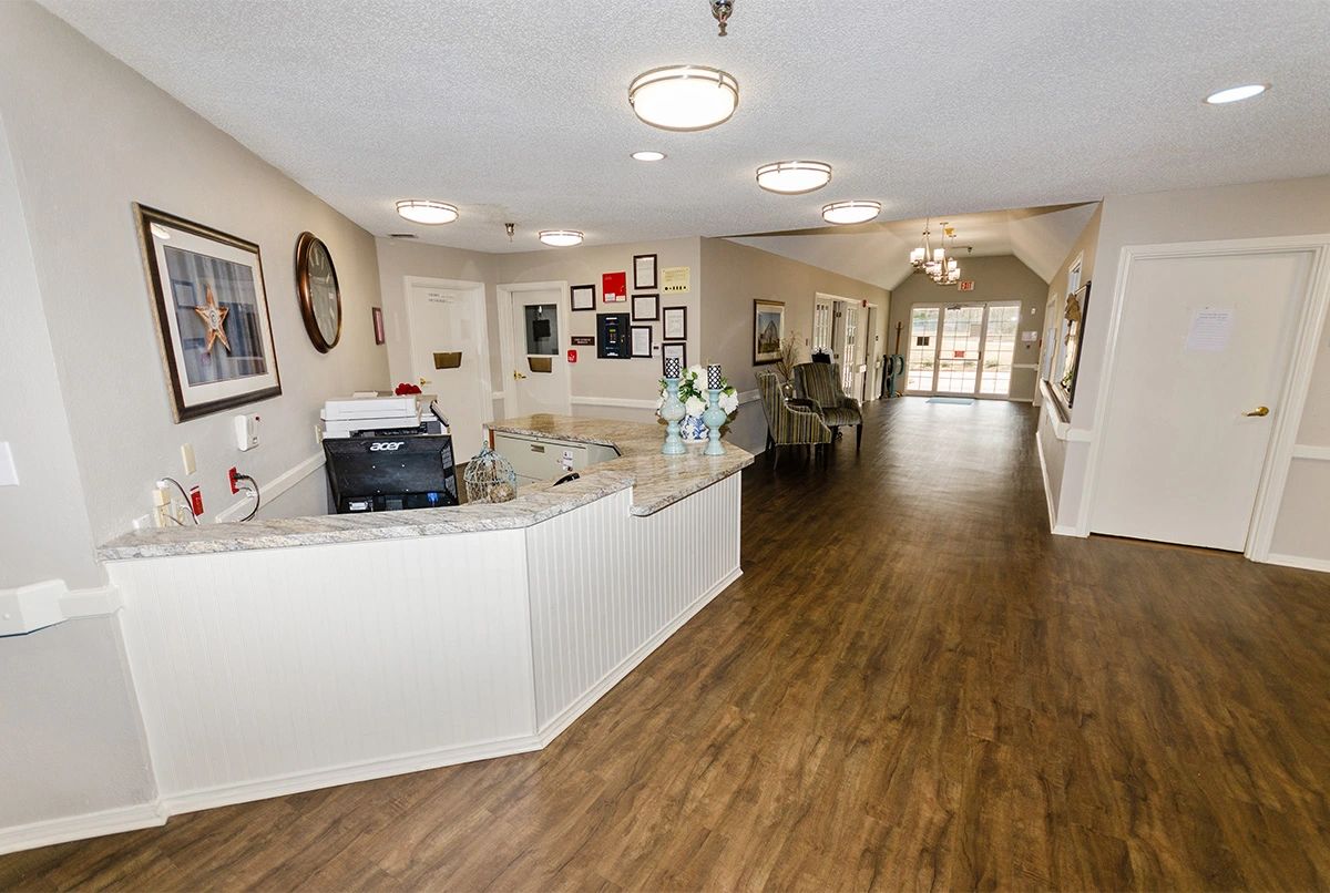 A spacious reception area with a desk, wooden flooring, and a waiting area in the background.
