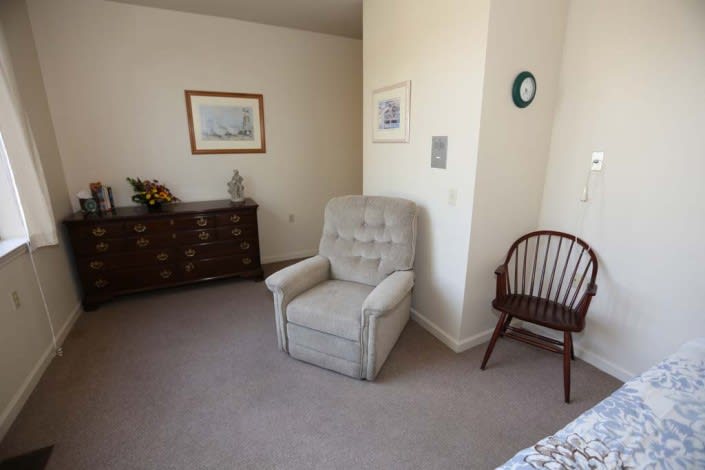 A cozy living room corner featuring an armchair, dresser, and wall decor.