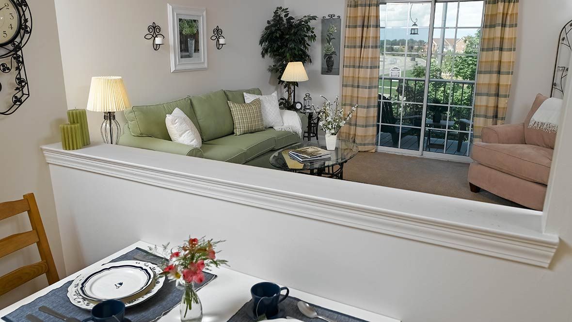 A cozy living room with a green sofa, table setting, and large window view.