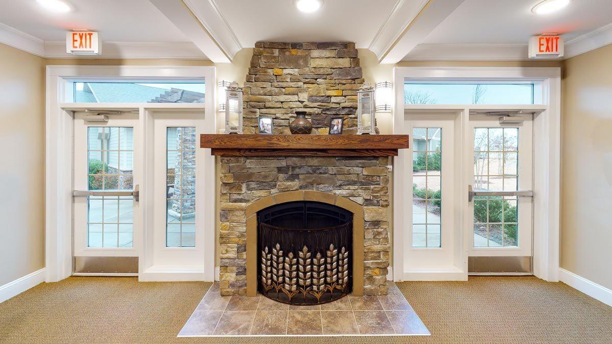 A beautifully designed stone fireplace with a wooden mantel, flanked by glass doors in a cozy living room setting.