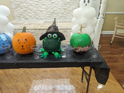 A colorful display of Halloween-themed pumpkins, including a traditional orange one and a creative green pumpkin dressed as a witch.