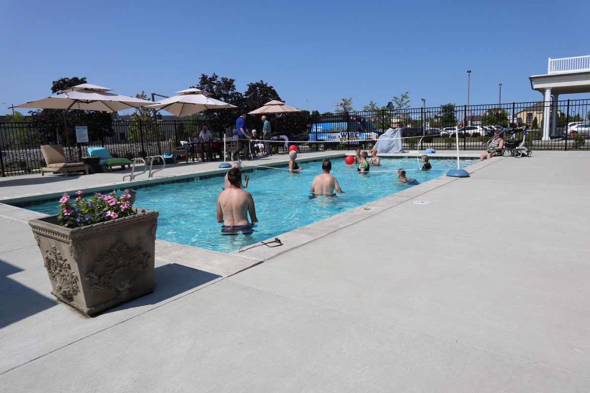 People enjoying a sunny day at the outdoor swimming pool.