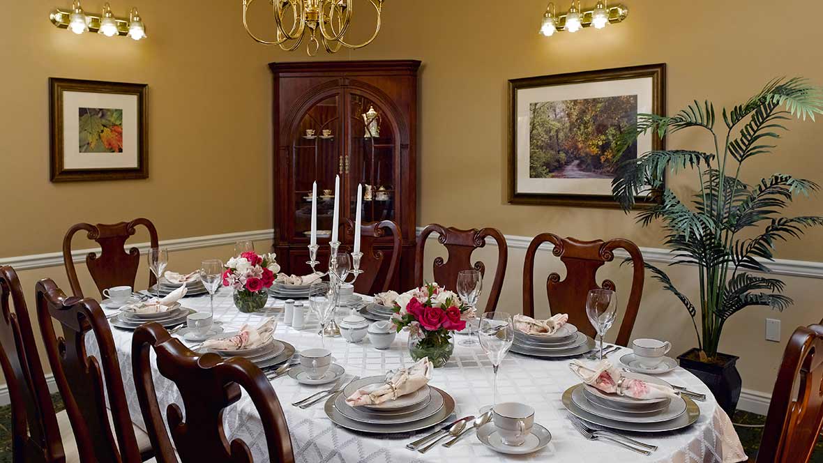 A formal dining room with a beautifully set table, featuring candlesticks and floral centerpieces.