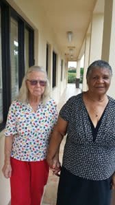 Two elderly women walking together, holding hands.