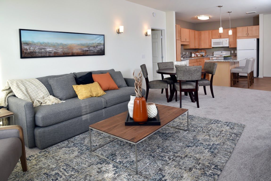 A modern open-concept living space featuring a comfortable sofa, stylish coffee table, and dining area leading into the kitchen.