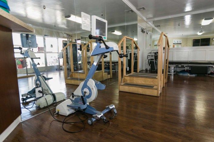 An exercise bike in a gym with wooden flooring and mirrored walls.