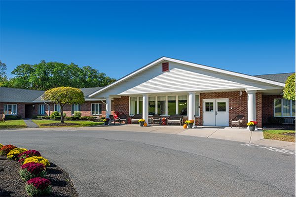 A building with a large entrance surrounded by a driveway and landscaped area under a clear blue sky.