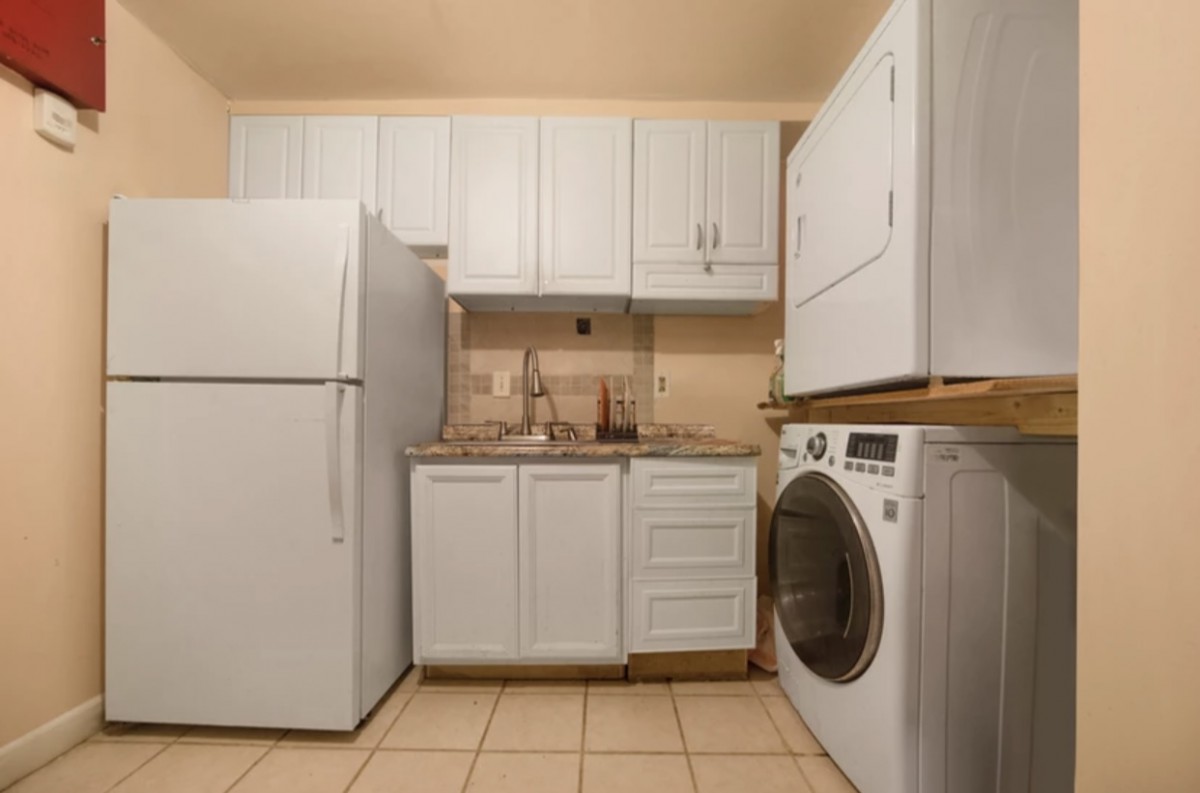 A compact laundry room with a washer, dryer, fridge, and white cabinetry.