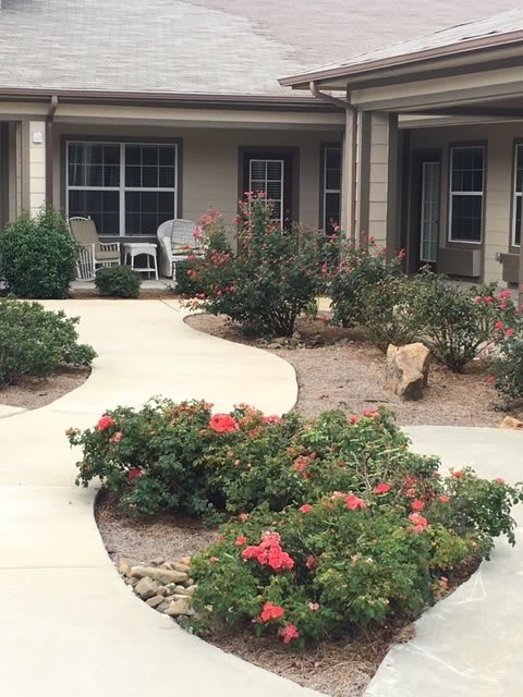 A beautifully landscaped garden with a winding pathway and blooming flowers in front of a house.