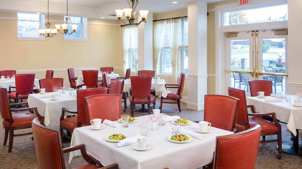 An elegant dining area with neatly arranged tables and red chairs.