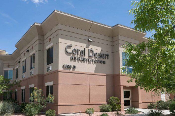 A medical building labeled Coral Desert Rehabilitation Center under a clear blue sky.