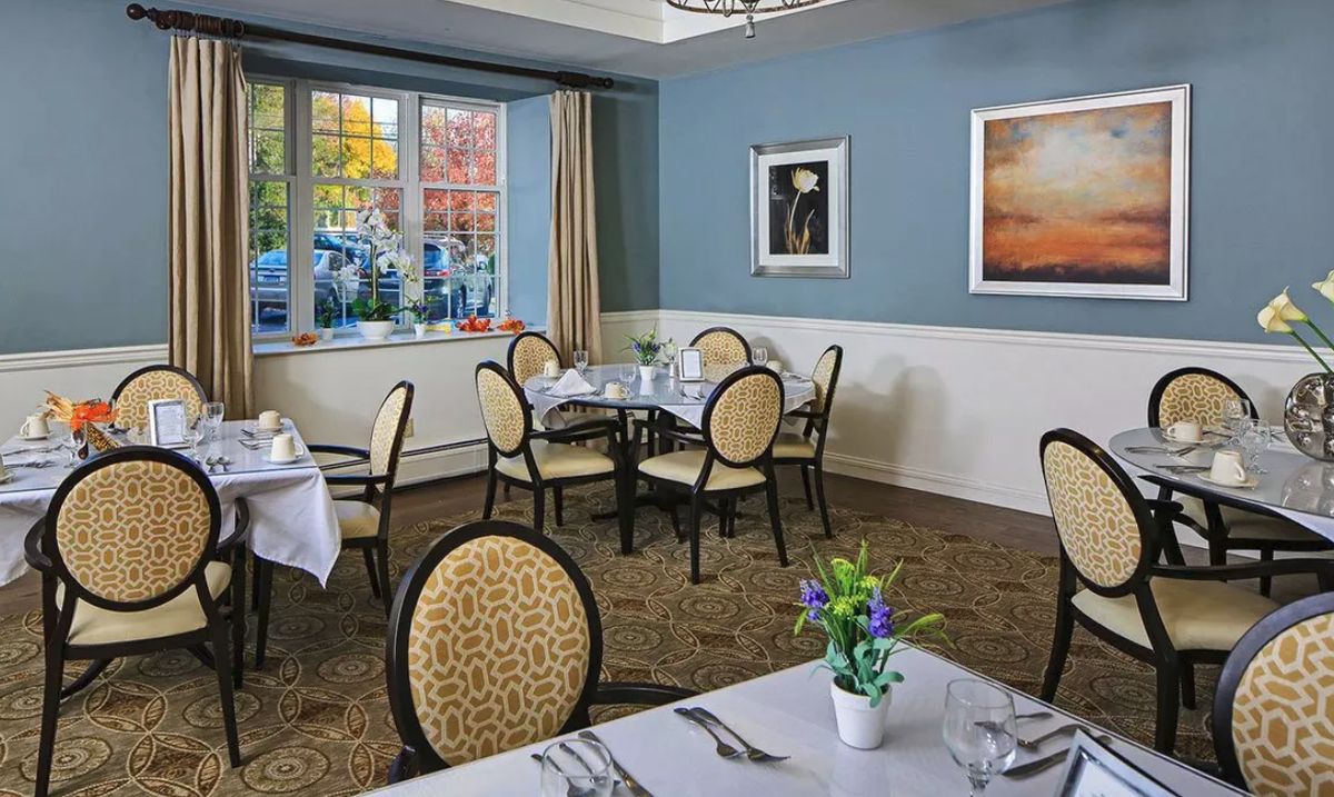 A cozy dining room with elegantly set tables and chairs, featuring soft lighting and tasteful decor.