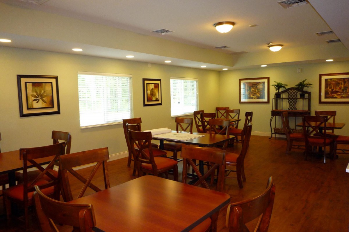 A cozy dining room with wooden tables and chairs, complemented by artwork on the walls and ample natural light.