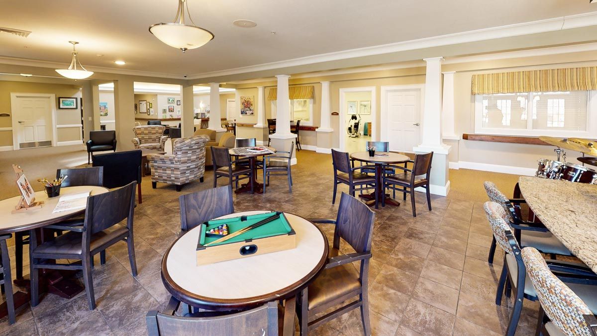 A communal lounge area with tables, chairs, and board games under warm indoor lighting.