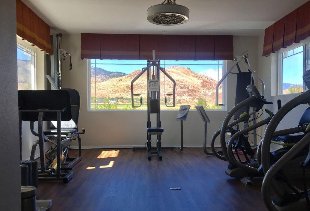 A home gym with exercise equipment and a stunning mountain view through the window.