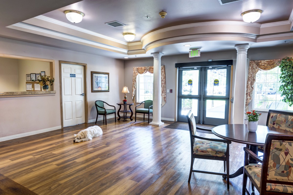 A spacious lobby area with wooden flooring, seating arrangements, and decorative lighting.