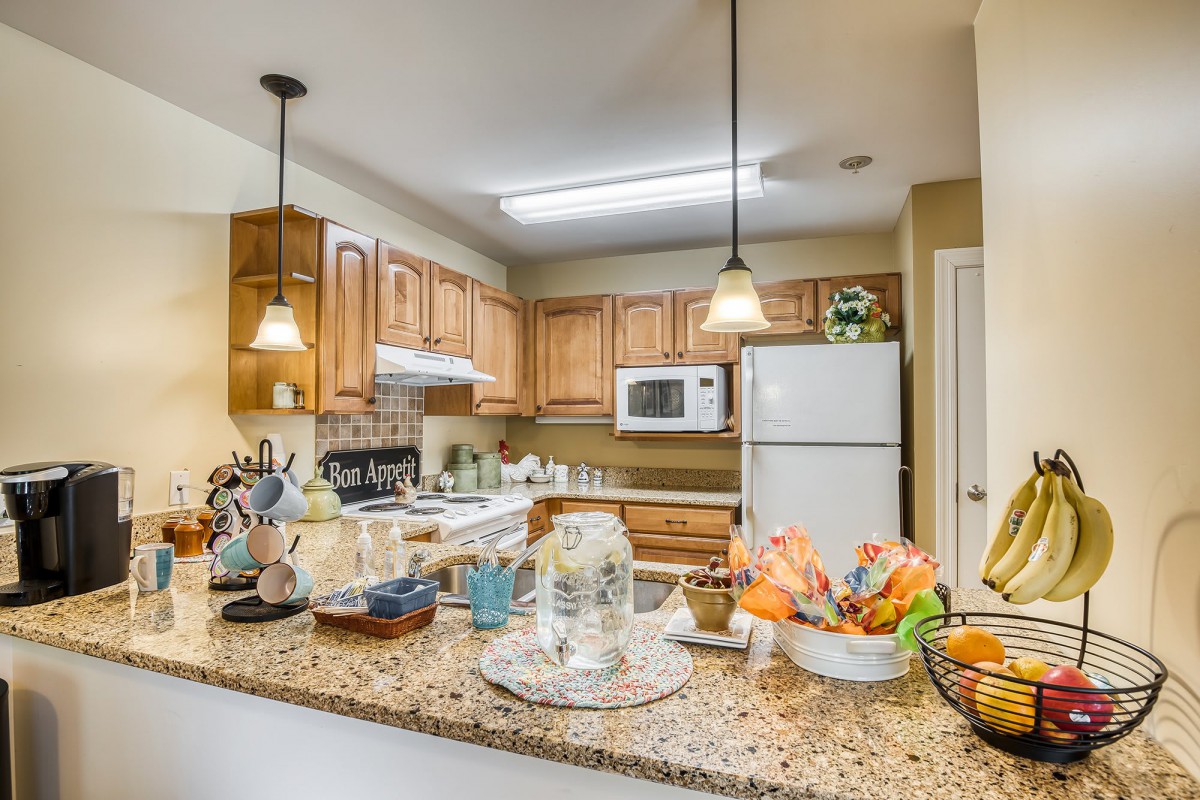 A cozy kitchen with wooden cabinets, granite countertops, and various appliances.