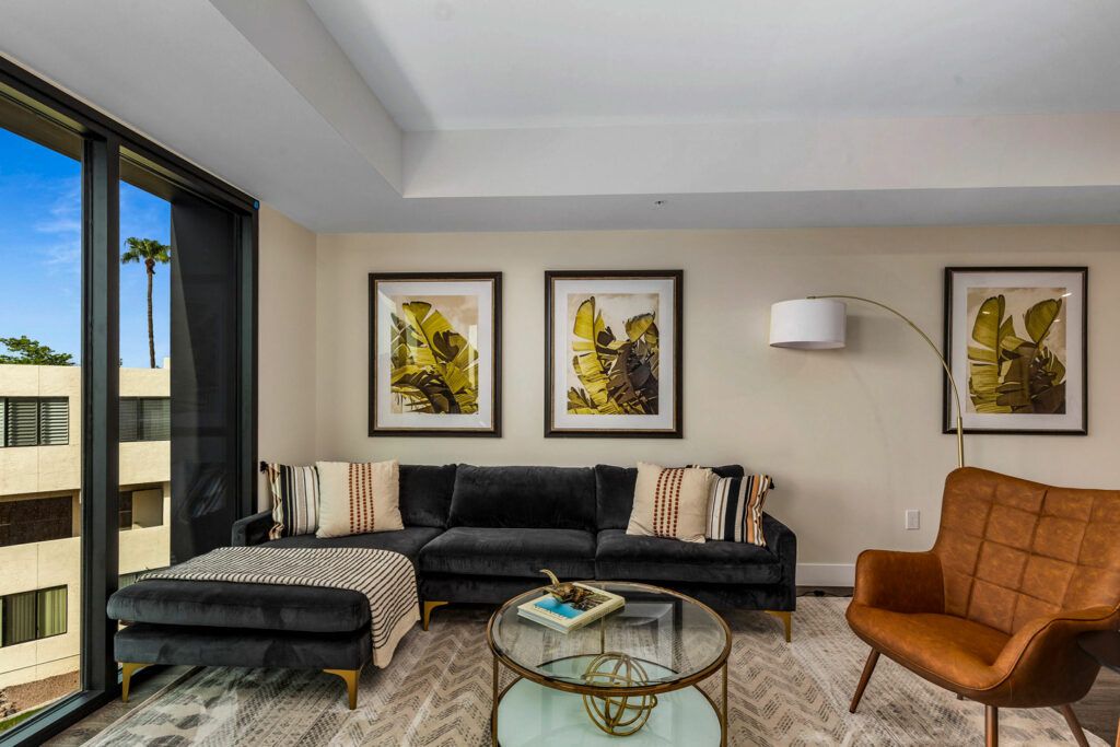 A modern living room with a black sofa, artistic wall decor, and a stylish coffee table.