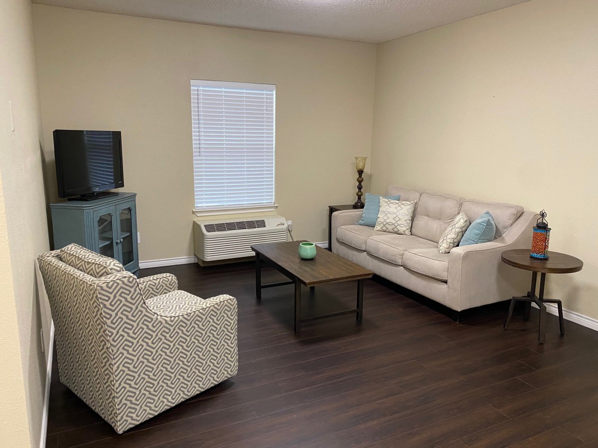 A cozy living room with a sofa, armchair, coffee table, and a TV.