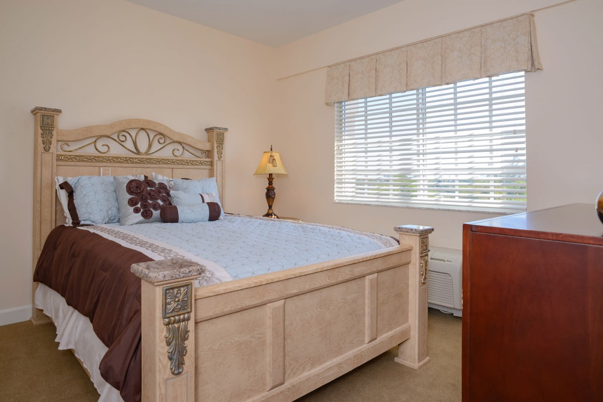 A cozy bedroom with a large bed, decorative pillows, and natural light from the window.