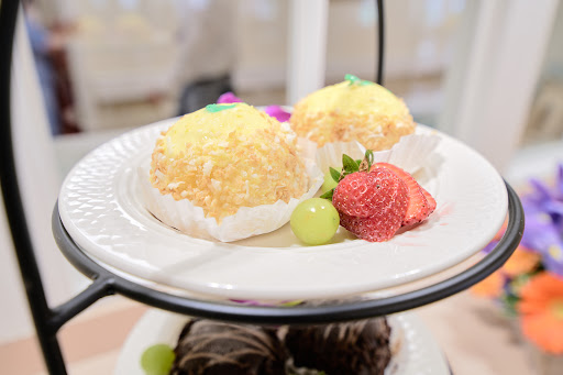 A delightful serving of sweet desserts, featuring creamy cakes topped with yellow sprinkles and accompanied by fresh strawberries.