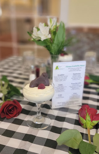A delightful dessert featuring whipped cream, topped with chocolate and raspberry, elegantly presented on a checkered tablecloth.