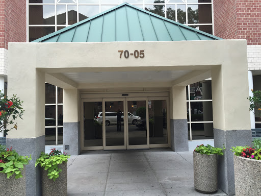 The entrance of a modern building featuring a distinctive roof and planters.
