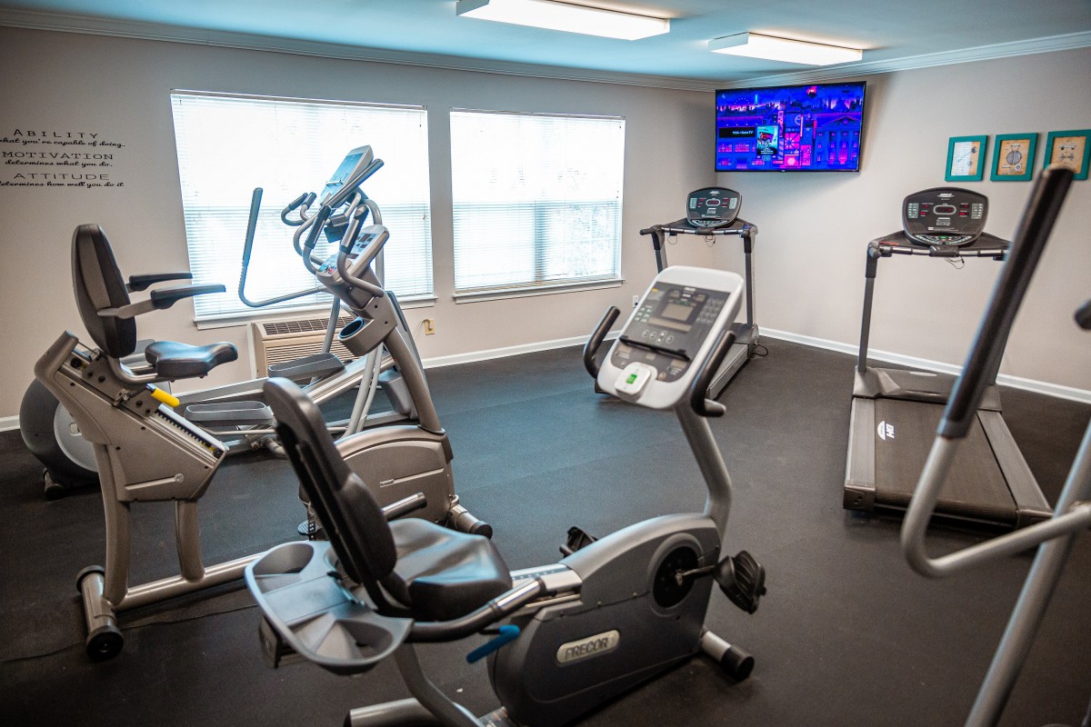 A compact fitness center with various exercise machines, including a treadmill, elliptical, and stationary bike.