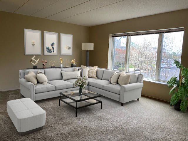 A modern living room with a neutral color palette, featuring a large sectional sofa and glass coffee table.