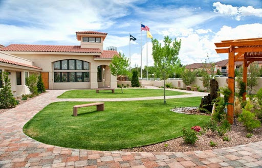 A serene outdoor space featuring a well-maintained lawn and a modern building with flags.