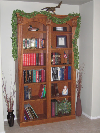 A beautifully arranged wooden bookshelf adorned with decorative plants and a variety of books.
