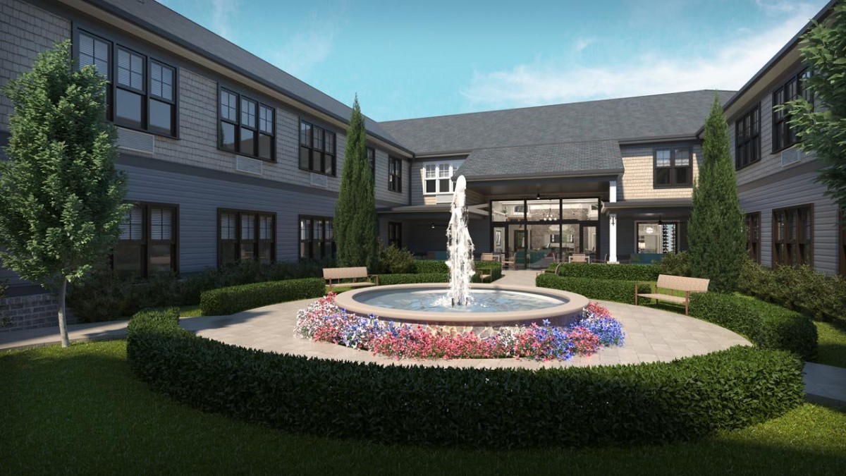 A beautifully landscaped courtyard featuring a central fountain surrounded by colorful flowers and well-maintained greenery.