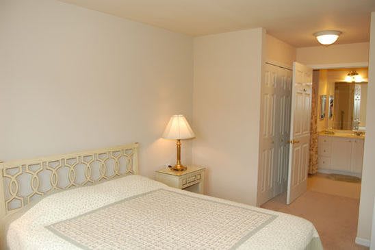 A cozy bedroom with a bed and a bedside lamp in a minimalist style.