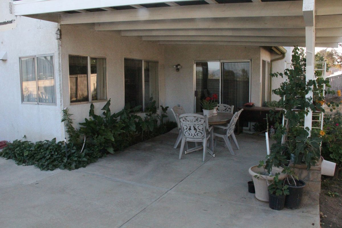 A cozy outdoor patio with a dining set and potted plants under a covered area.