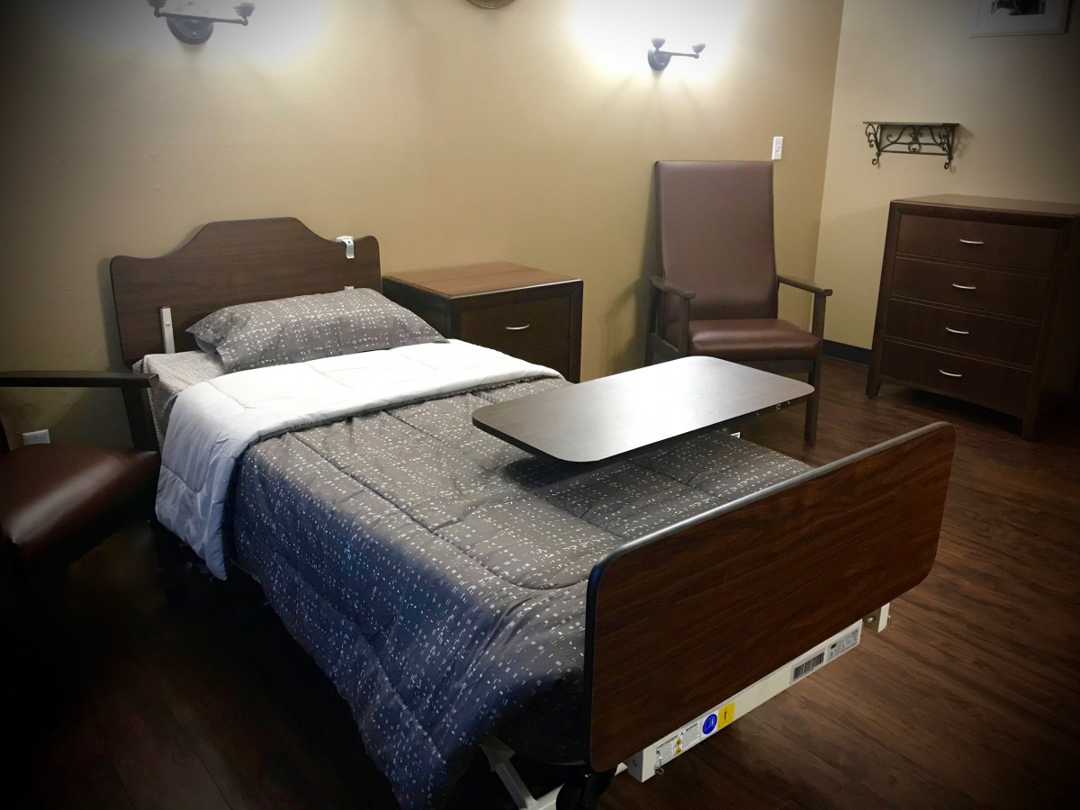 A hospital room featuring a single bed with medical accessories and furniture.