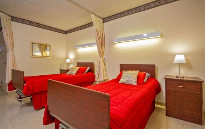A modern bedroom with twin beds featuring red bedding and soft lighting.