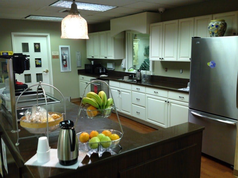A modern kitchen with white cabinetry and a countertop displaying fresh fruits and a coffee pot.
