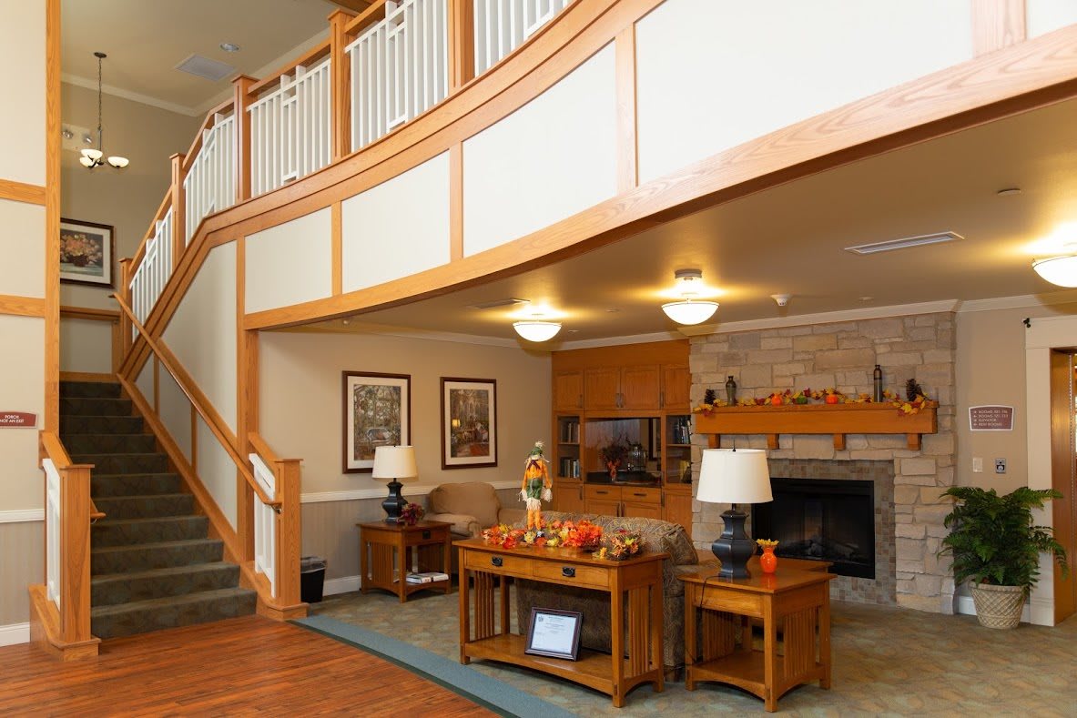 A cozy living room with a staircase and fireplace, featuring wood accents and home decor.